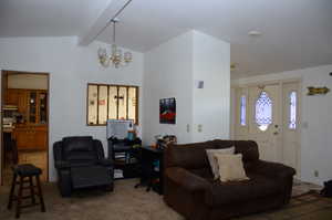 Living area with vaulted ceiling with beams, an inviting chandelier, and carpet floors