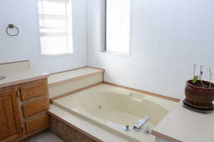 Bathroom featuring a tub with jets and vanity