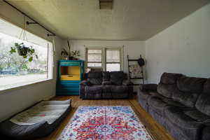 Living area featuring visible vents, wood finished floors, and a textured ceiling