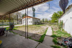 View of yard featuring a patio, a fenced backyard, and an outbuilding