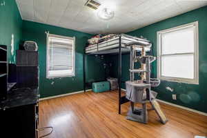 Bedroom with visible vents, wood finished floors, and baseboards