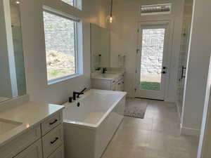 Bathroom featuring a sink, a stall shower, two vanities, a freestanding bath, and tile patterned flooring
