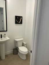 Half bath featuring toilet, tile patterned flooring, and baseboards