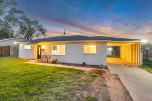 View of front of home with fence, a shingled roof, a carport, a yard, and driveway