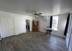 Interior space with a ceiling fan, visible vents, wood finished floors, and baseboards