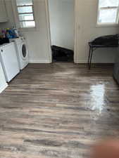 Clothes washing area featuring dark wood finished floors, baseboards, and washer and clothes dryer