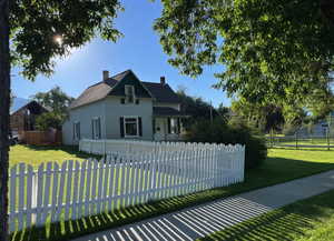 View of front facade with a chimney, a front lawn, and a fenced front yard