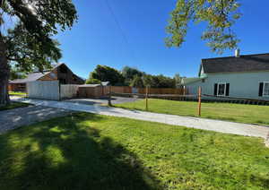 View of yard with fence, a shed, and an outbuilding