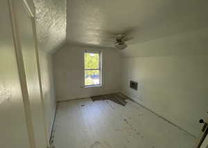 Bonus room with vaulted ceiling, baseboards, visible vents, a ceiling fan, and a textured ceiling