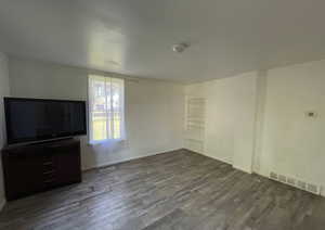 Unfurnished living room featuring baseboards, visible vents, and wood finished floors