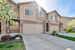 View of front of house featuring stone siding, stucco siding, concrete driveway, and an attached garage