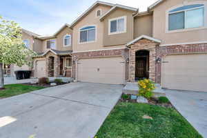 View of front of home featuring stucco siding, concrete driveway, an attached garage, and stone siding