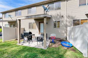 Back of property with fence, a lawn, and a patio area