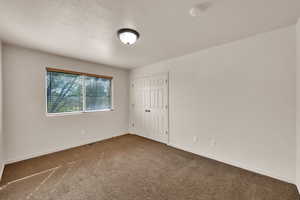 Carpeted spare room featuring visible vents and baseboards