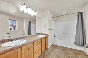 Bathroom with double vanity, shower / tub combo with curtain, visible vents, and a sink