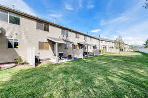 Back of house featuring a patio area, a residential view, a lawn, central AC, and fence