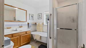 Full bathroom with a shower stall, toilet, vanity, tile walls, and a soaking tub