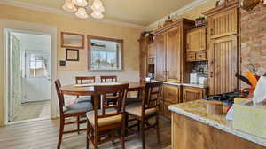 Kitchen featuring light wood-style flooring, a chandelier, a wainscoted wall, and crown molding