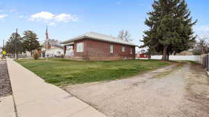 View of property exterior with brick, fence, a yard, and driveway