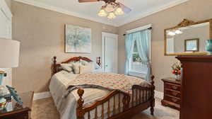 Bedroom featuring a textured wall, a ceiling fan, carpet floors, crown molding, and baseboards