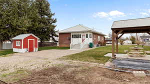 Rear view of house featuring a lawn, an outdoor structure, a shed, and metal roof