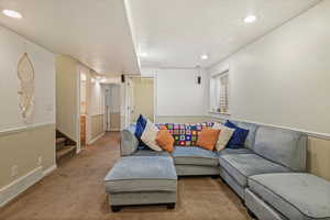Living area with carpet flooring, stairway, visible vents, baseboards, and recessed lighting