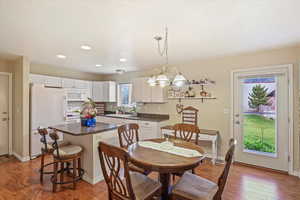 Dining room with recessed lighting, an inviting chandelier, and dark wood-type flooring