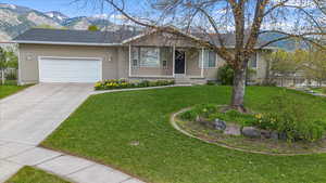 Ranch-style house with a front lawn, driveway, an attached garage, and a mountain view