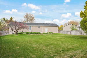 Back of house with a fenced backyard and a yard