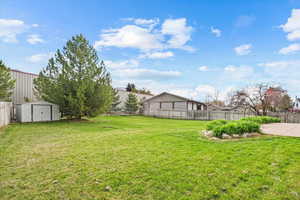 View of yard with a storage unit, a fenced backyard.