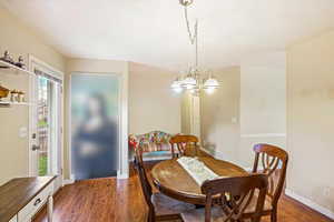 Dining space featuring an inviting chandelier, dark wood finished floors.