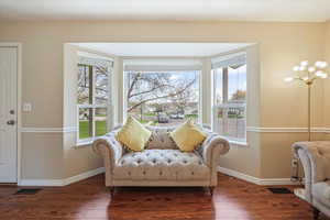 Sitting room with baseboards, wood finished floors, and a healthy amount of sunlight
