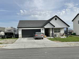 View of front facade featuring roof with shingles, driveway, an attached garage, and stone siding