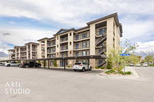 View of apartment building / complex featuring covered parking