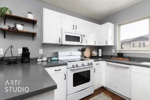 Kitchen featuring white cabinetry, dark countertops, white appliances, and dark wood-type flooring