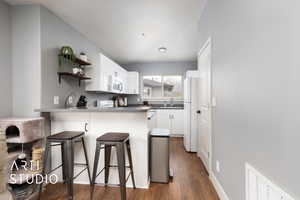 Kitchen with a sink, open shelves, a breakfast bar, a peninsula, and white appliances