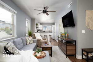 Living area featuring visible vents, a ceiling fan, baseboards, and light wood-style floors