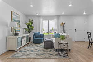 Living room with light wood finished floors, recessed lighting, and baseboards