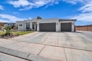 View of front facade featuring stucco siding, fence, concrete driveway, and a garage