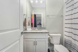 A beautifully designed en suite bathroom featuring bright, airy details and elegant granite countertop.