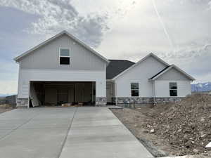 Modern farmhouse with driveway, a garage, board and batten siding, and stone siding