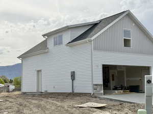 View of side of home featuring a mountain view and roof with shingles