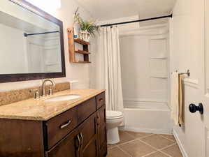 Full bathroom with vanity, toilet, tile patterned floors, and shower / bath combo