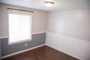 Unfurnished room with dark wood-style flooring, plenty of natural light, and baseboards