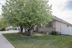 View of front facade with brick siding, fence, driveway, a front lawn, and an attached garage