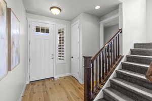 Foyer entrance featuring light wood-style floors, visible vents, baseboards, recessed lighting, and stairs