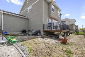 Rear view of property featuring central air condition unit, a deck, stucco siding, and fence