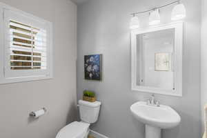 Half bath featuring toilet, baseboards, and a sink