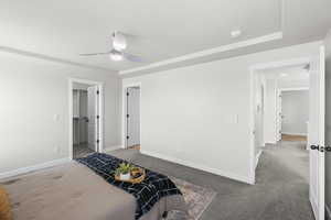 Bedroom with baseboards, a ceiling fan, a walk in closet, and light colored carpet