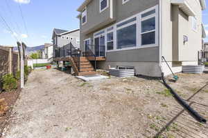 Back of house with stairs, a residential view, a deck, stucco siding, and fence
